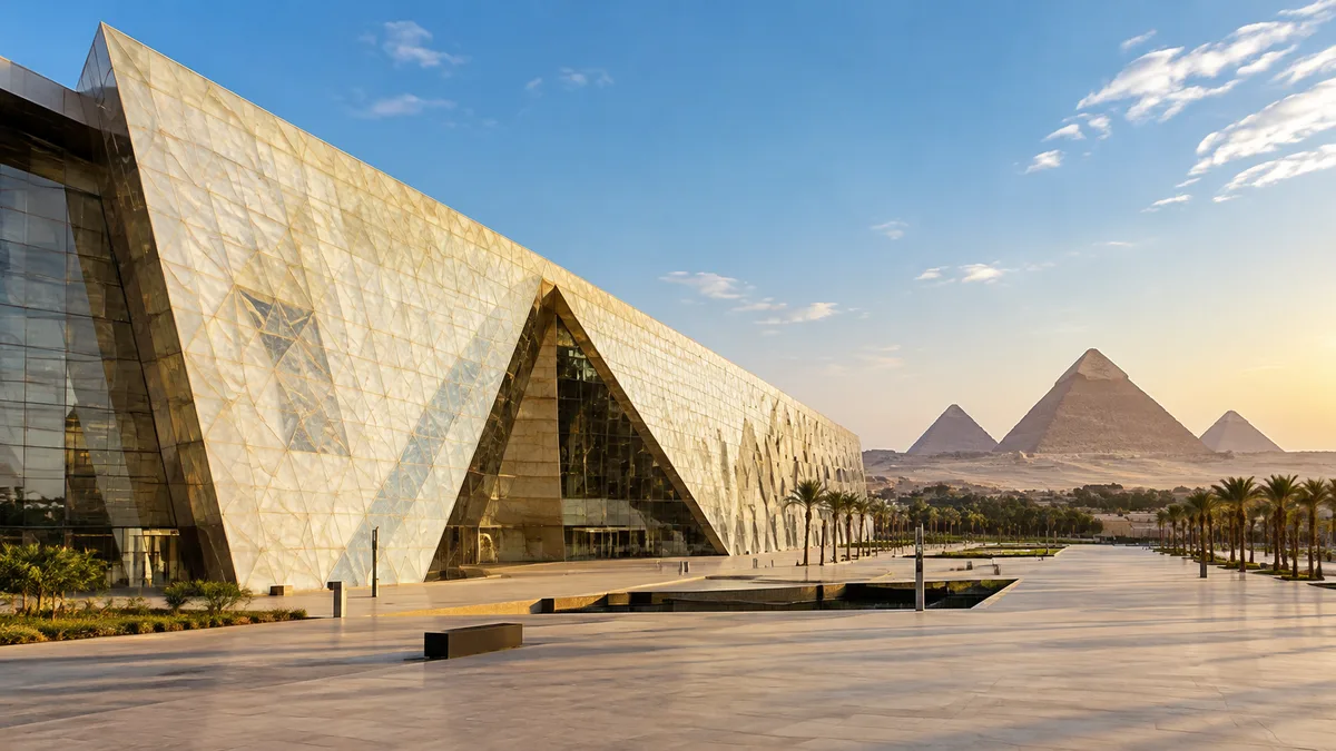 Un immense musée moderne à la façade pâle et inclinée, avec les pyramides de Gizeh à l'horizon