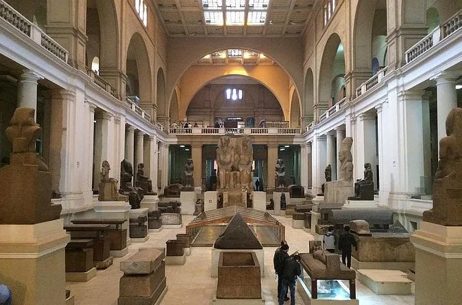 Une longue salle du rez-de-chaussée du Musée égyptien avec des statues de pierre et des sarcophages sous un toit de verre